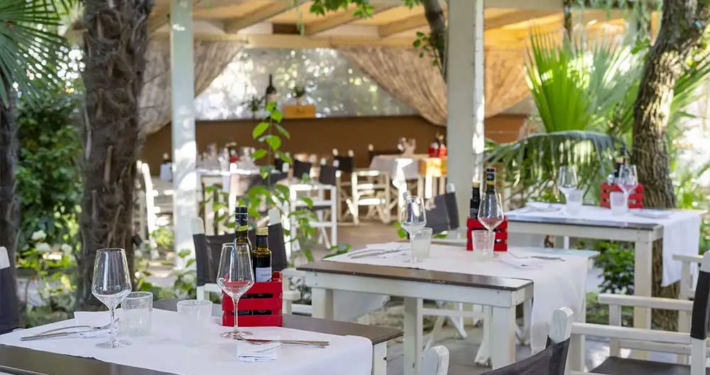 Große, überdachte Terrasse des Ristorante Arginvecchio in der Toskana mit Blick auf den weitläufigen Garten, perfekt für ein entspanntes Abendessen im Freien.