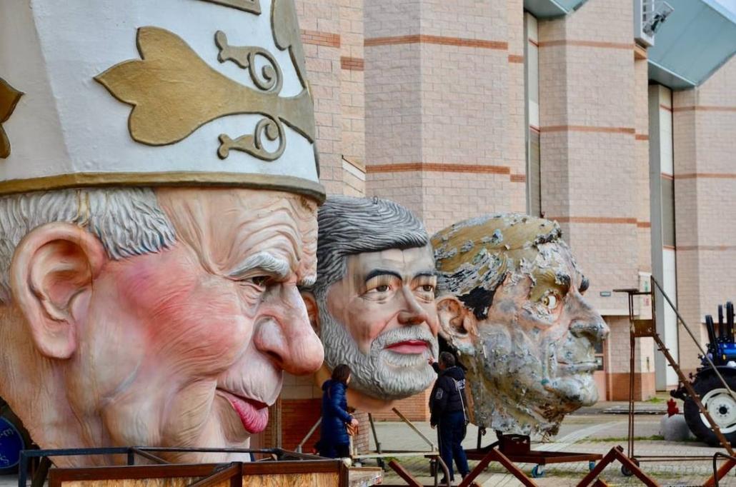 Teste giganti in cartapesta esposte davanti a un hangar della Cittadella del Carnevale di Viareggio